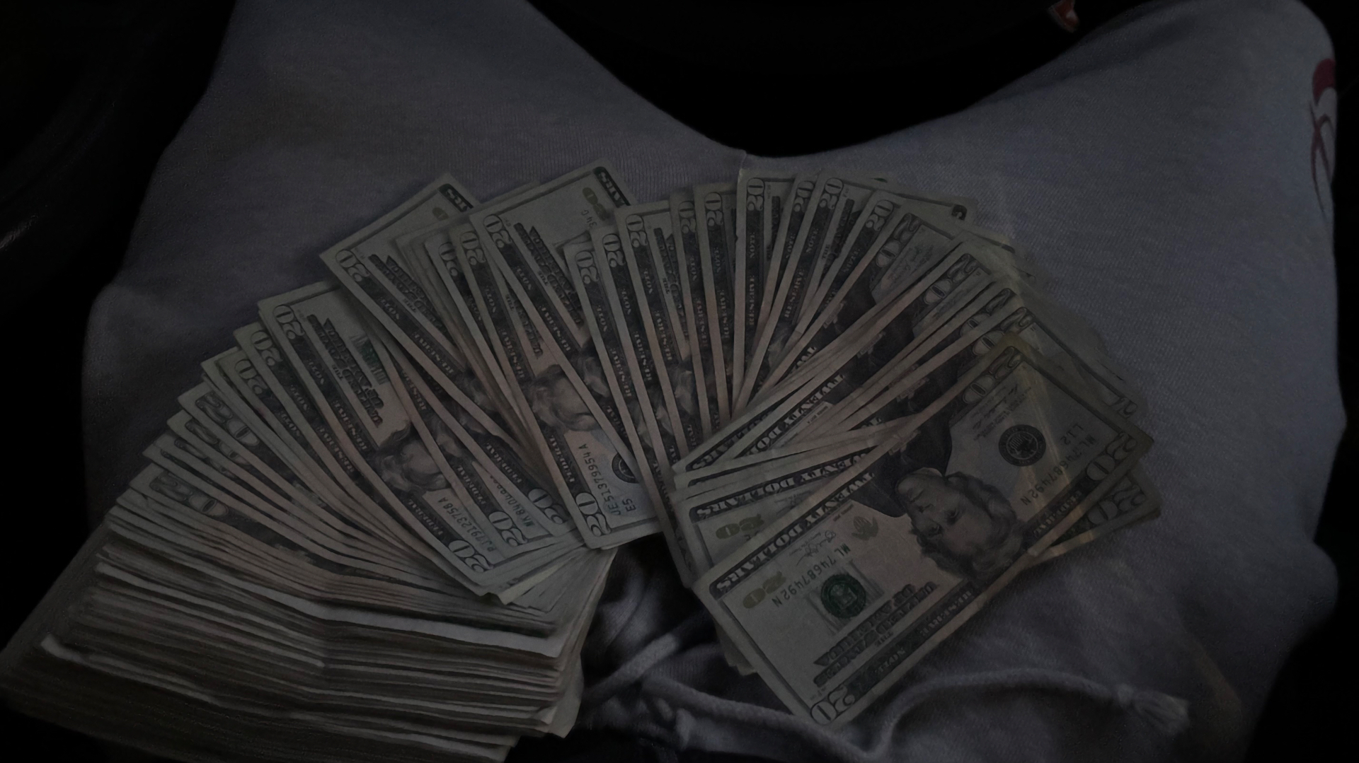 Fan of twenty-dollar bills held in a reseller's lap after a profitable moissanite vendor run